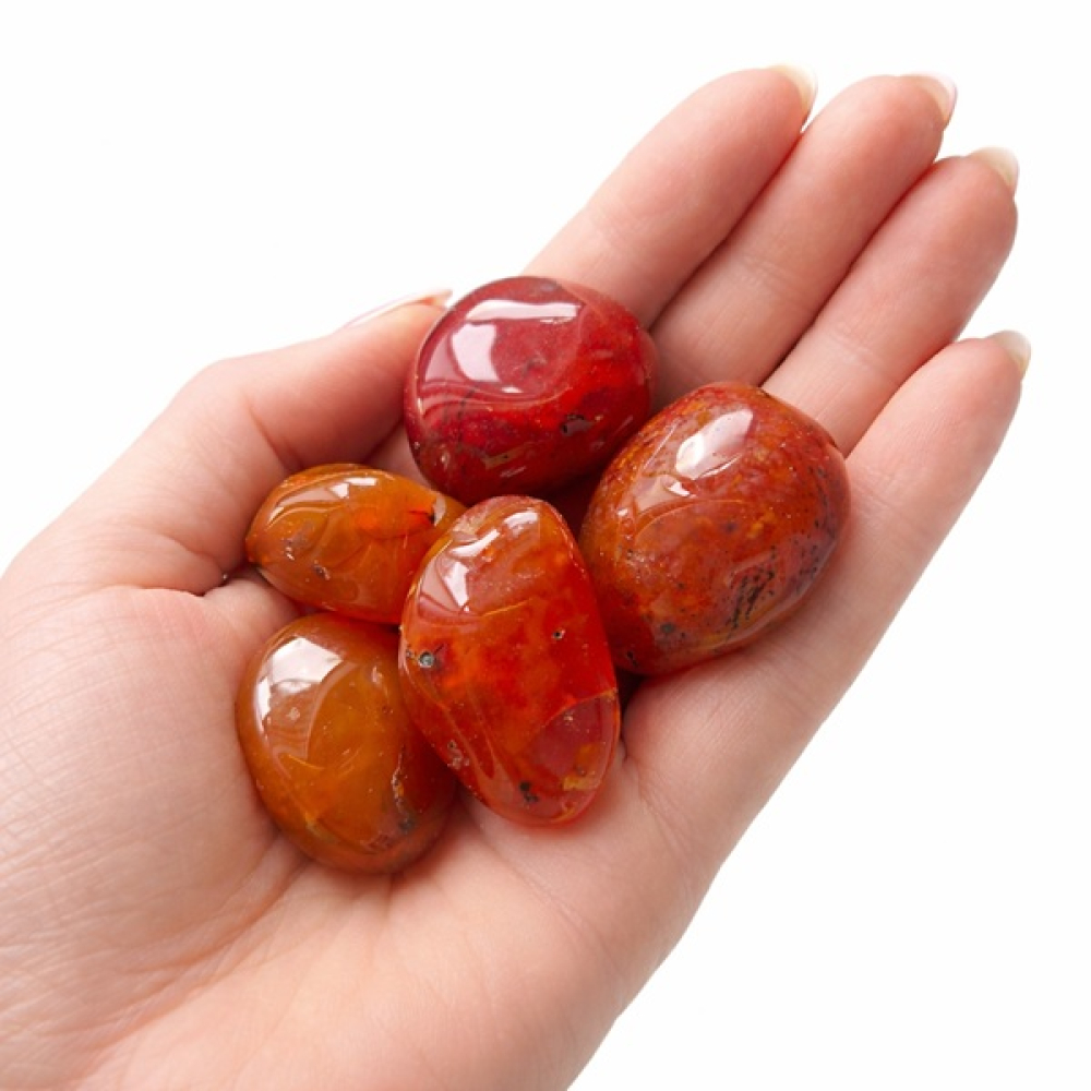 Karneol Trommelsteine in einer Hand als Größenvergleich